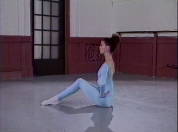 A woman in blue leotards sitting on the ground.
