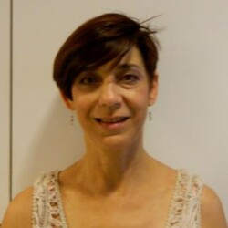 A woman with short hair wearing a white top.