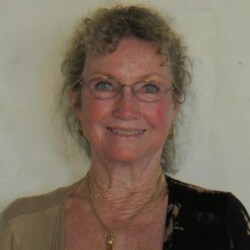 A woman with glasses and curly hair wearing a necklace.