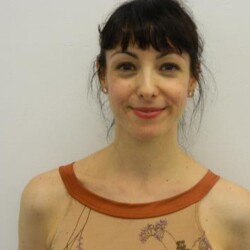 A woman with brown hair and a tattoo on her chest.