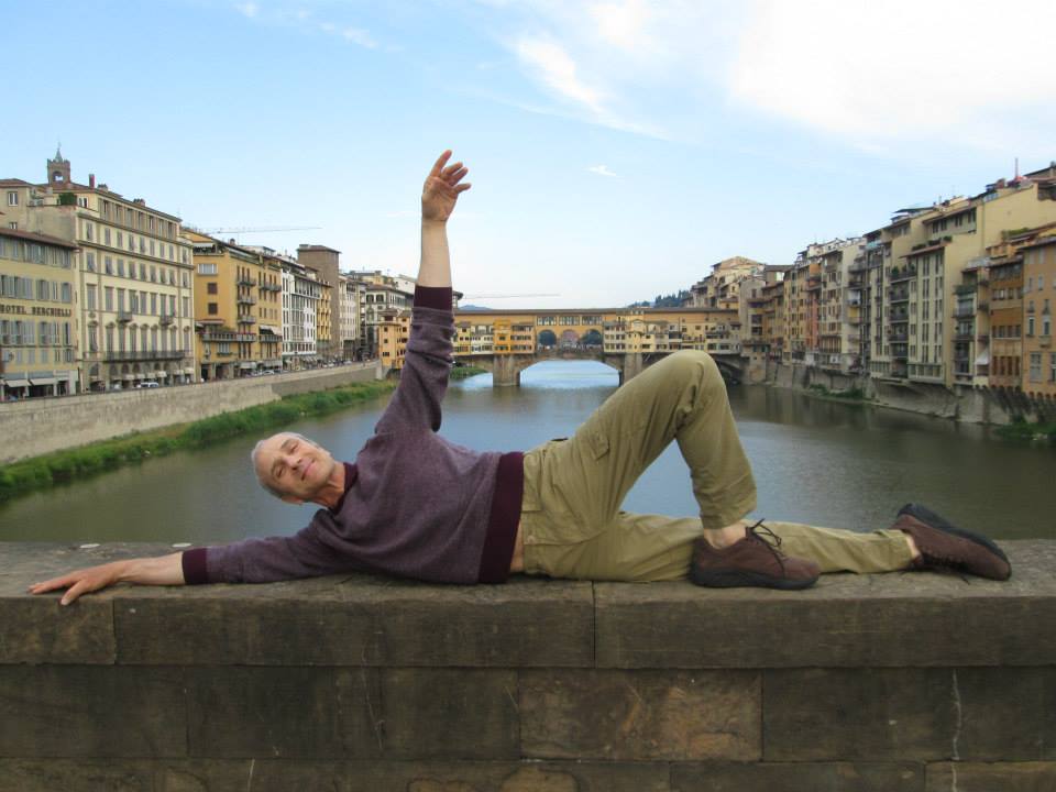 A Man Performing Floor Barre Technique on Bridge with Ponte Vecchio in the Back