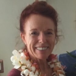 A woman with red hair and a flower lei around her neck.
