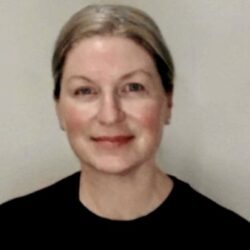 Smiling person with short hair, neutral background.